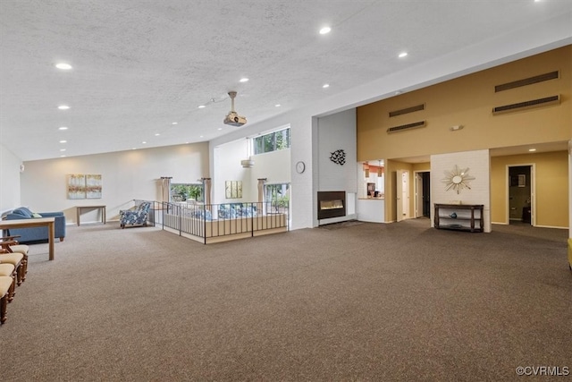 carpeted living room with a towering ceiling, a textured ceiling, and a fireplace