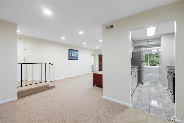 hallway featuring light carpet and a skylight