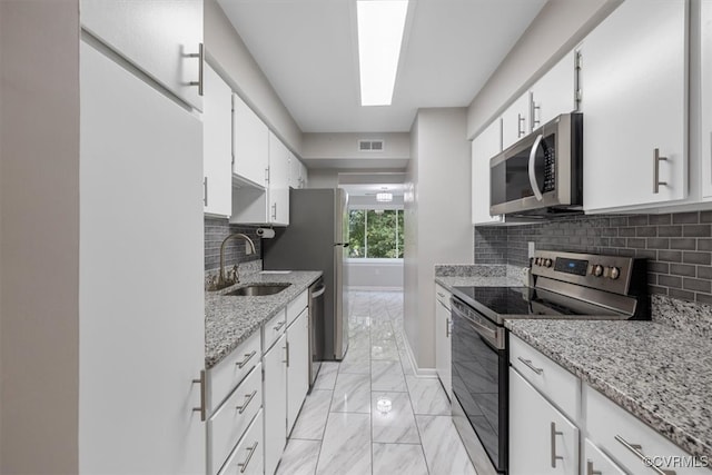 kitchen featuring appliances with stainless steel finishes, white cabinetry, tasteful backsplash, and sink