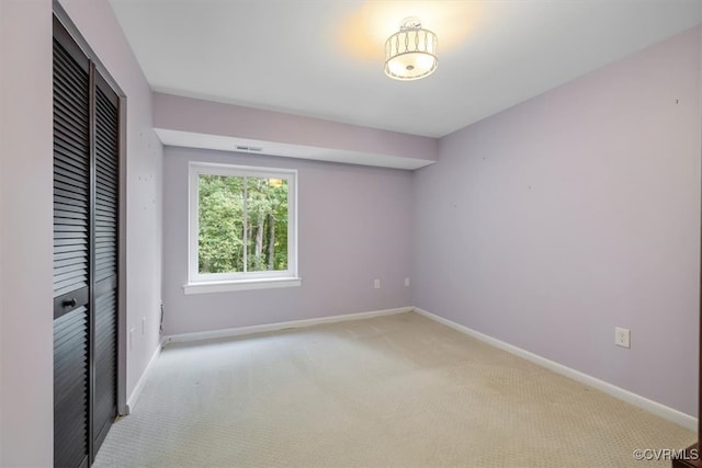 unfurnished bedroom with light colored carpet and a closet