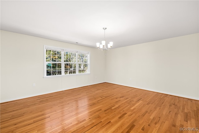 spare room with light hardwood / wood-style floors and a chandelier