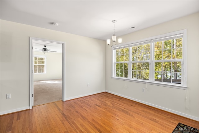 spare room with light hardwood / wood-style floors and ceiling fan with notable chandelier