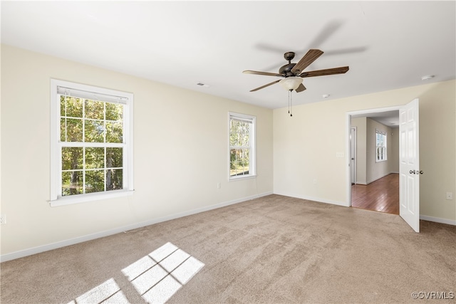 carpeted spare room featuring ceiling fan and a wealth of natural light