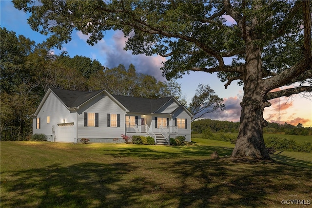 back house at dusk with a garage and a lawn