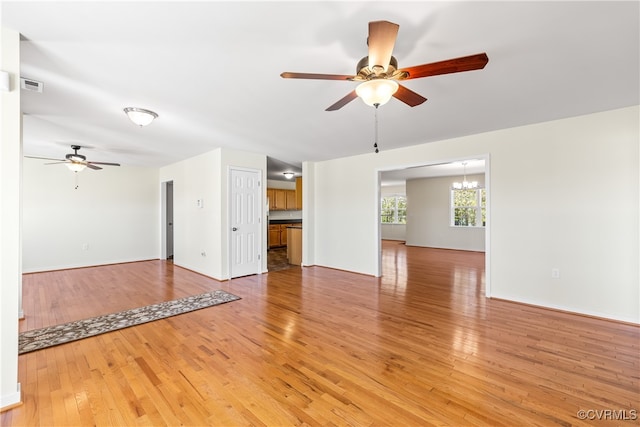 unfurnished living room featuring wood-type flooring and ceiling fan with notable chandelier