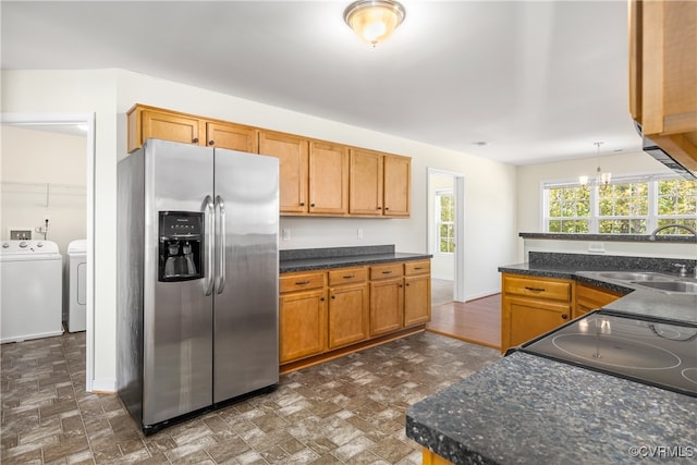 kitchen with sink, independent washer and dryer, decorative light fixtures, a chandelier, and stainless steel refrigerator with ice dispenser