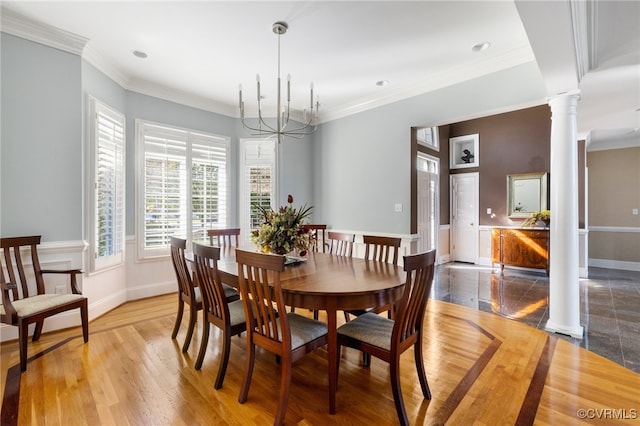 dining area with crown molding, ornate columns, a notable chandelier, and light wood-type flooring