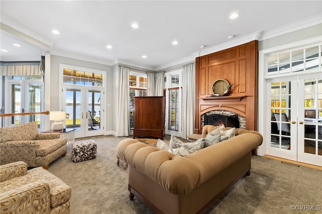 living room featuring french doors, crown molding, a large fireplace, and carpet floors