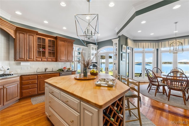 kitchen with a kitchen island, wood counters, light wood-type flooring, an inviting chandelier, and a water view