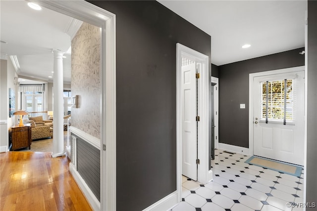 hall featuring ornamental molding, ornate columns, and light wood-type flooring