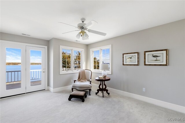 living area with a water view, light carpet, and a healthy amount of sunlight