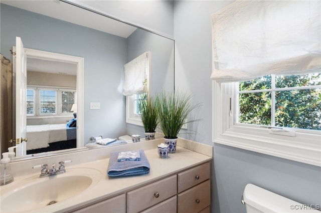 bathroom featuring toilet, a healthy amount of sunlight, and vanity