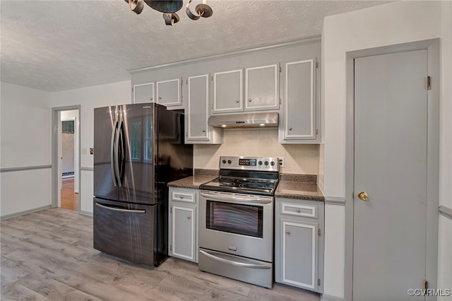 kitchen with a textured ceiling, light hardwood / wood-style flooring, decorative backsplash, and stainless steel appliances