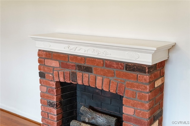 interior details with a brick fireplace and wood-type flooring