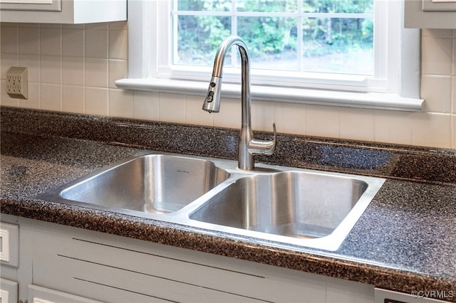 room details with white cabinetry, tasteful backsplash, and sink