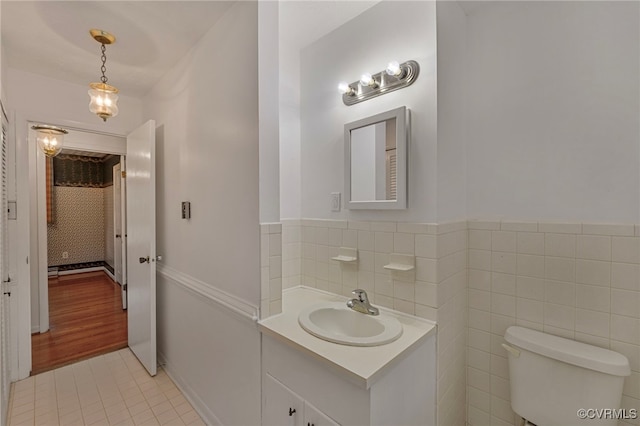 bathroom with tile walls, vanity, toilet, and tile patterned floors