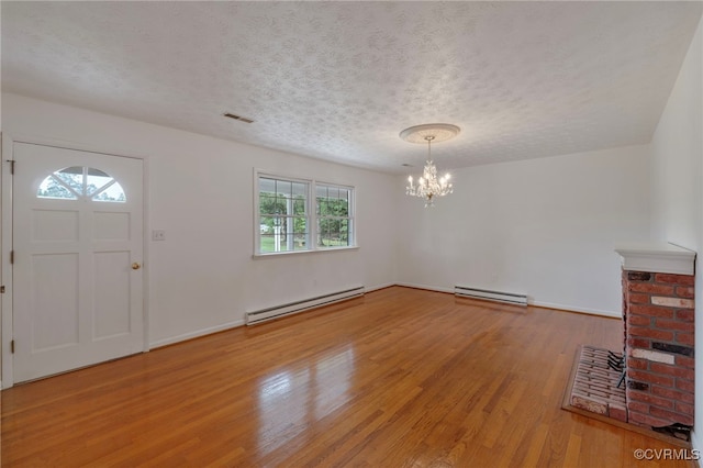 entryway featuring a textured ceiling, baseboard heating, wood-type flooring, and a fireplace