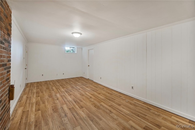 empty room featuring light hardwood / wood-style flooring, ornamental molding, and brick wall