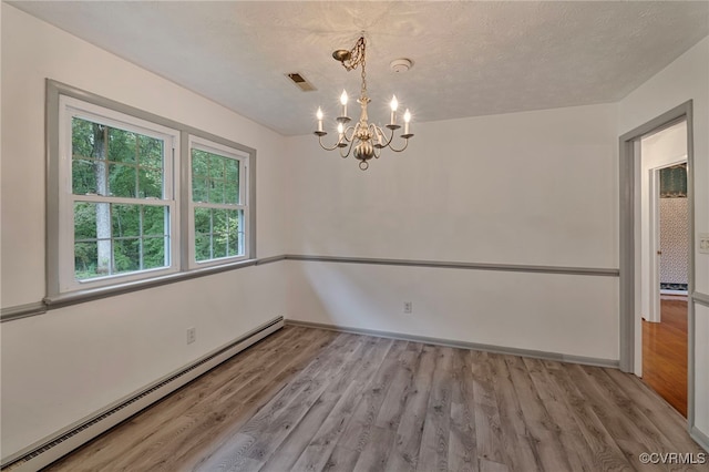 spare room with a chandelier, a baseboard heating unit, a textured ceiling, and light hardwood / wood-style floors