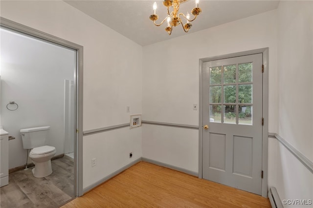 doorway featuring light hardwood / wood-style floors, a notable chandelier, and a baseboard heating unit