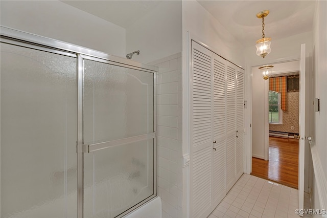 bathroom featuring a baseboard radiator, hardwood / wood-style floors, and shower / bath combination with glass door