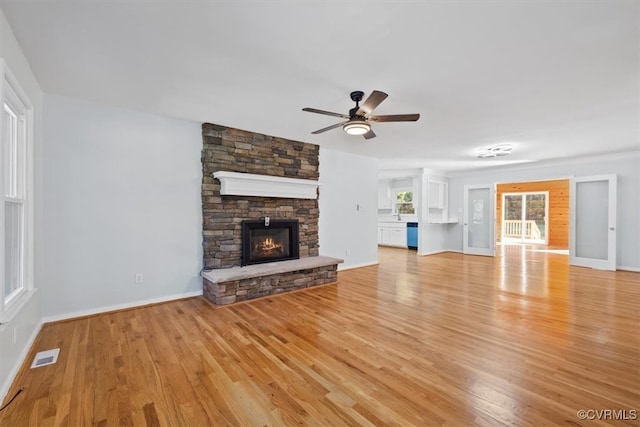 unfurnished living room with a fireplace, light wood-type flooring, and ceiling fan