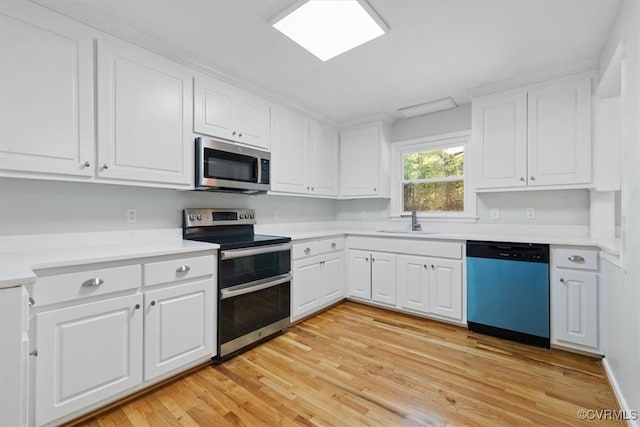 kitchen with sink, appliances with stainless steel finishes, white cabinetry, and light wood-type flooring