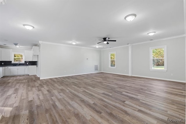 unfurnished living room with crown molding, light hardwood / wood-style flooring, ceiling fan, and plenty of natural light