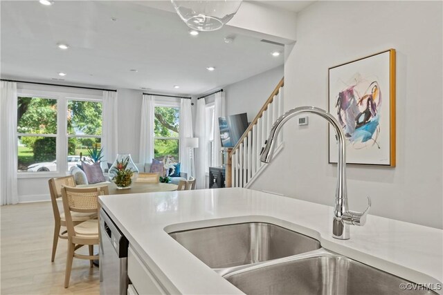 kitchen with sink, stainless steel dishwasher, plenty of natural light, and light wood-type flooring