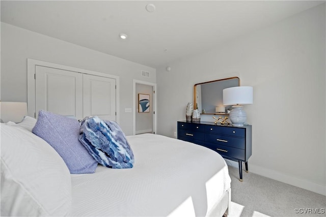 bedroom with a closet, light carpet, visible vents, and baseboards