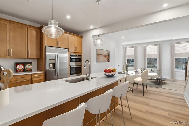 kitchen featuring decorative light fixtures, light hardwood / wood-style floors, sink, and stainless steel appliances