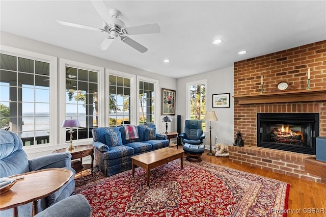 living room with hardwood / wood-style floors, a brick fireplace, a wealth of natural light, and ceiling fan