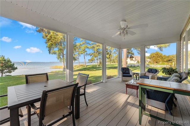 wooden deck with ceiling fan, a yard, and a water view