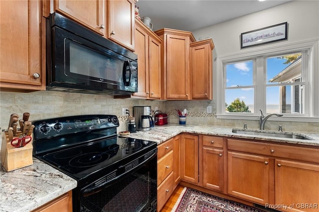 kitchen featuring sink, tasteful backsplash, light stone counters, and black appliances