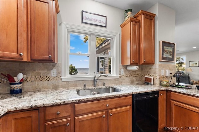 kitchen featuring backsplash, light stone counters, dishwasher, and sink