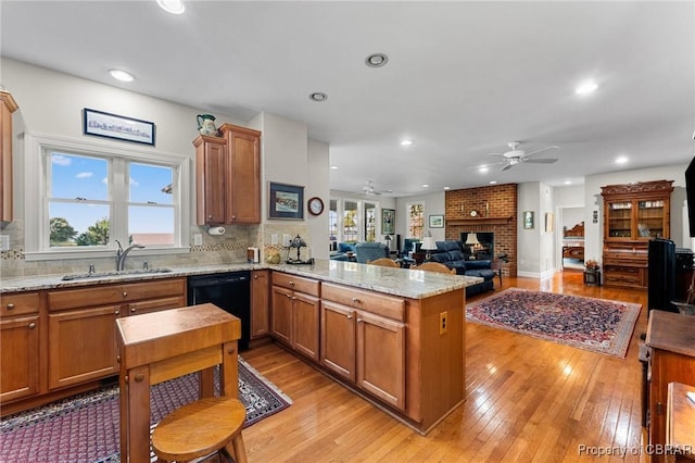 kitchen with kitchen peninsula, a wealth of natural light, sink, and black dishwasher