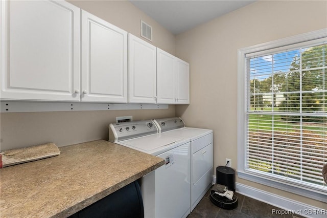 laundry area featuring separate washer and dryer, dark tile patterned floors, and cabinets