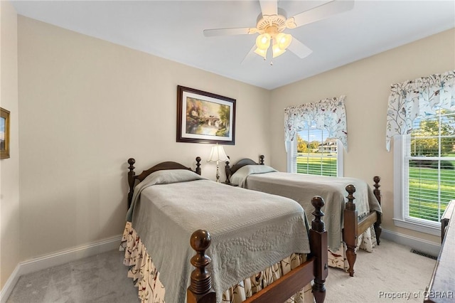 bedroom with ceiling fan, light colored carpet, and multiple windows