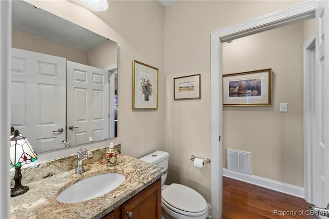 bathroom featuring toilet, vanity, and hardwood / wood-style flooring