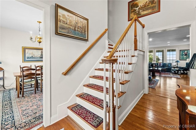 staircase featuring hardwood / wood-style floors and an inviting chandelier