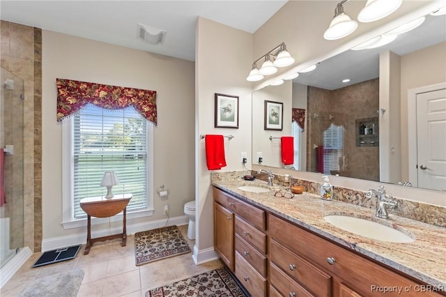 bathroom featuring tile patterned flooring, vanity, toilet, and a shower with door