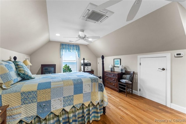 bedroom with ceiling fan, hardwood / wood-style floors, and vaulted ceiling