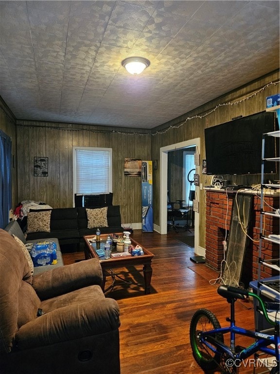 living room with a fireplace, wooden walls, and dark hardwood / wood-style floors