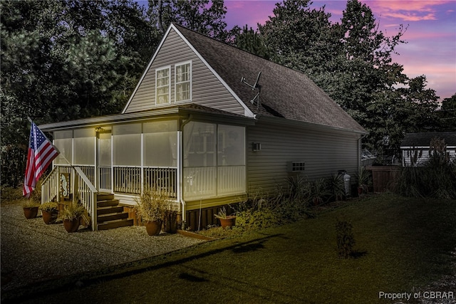 back house at dusk with a sunroom