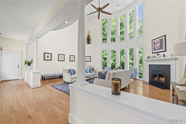 living room featuring a towering ceiling, ceiling fan, and light hardwood / wood-style flooring