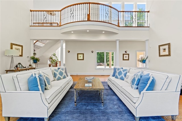 living room with a towering ceiling, hardwood / wood-style flooring, and decorative columns