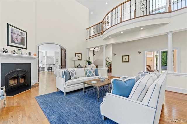 living room featuring ornate columns, hardwood / wood-style flooring, and a high ceiling