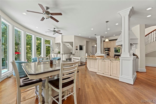 dining area featuring a wealth of natural light, ceiling fan, decorative columns, and light hardwood / wood-style flooring