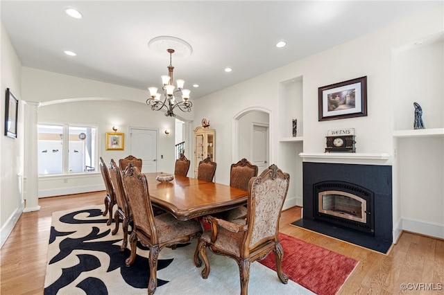 dining space featuring ornate columns, an inviting chandelier, and light hardwood / wood-style floors