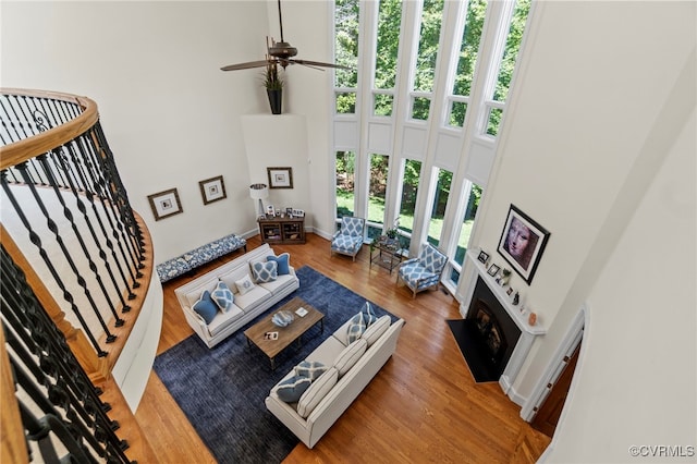 living room with ceiling fan, a towering ceiling, and wood-type flooring